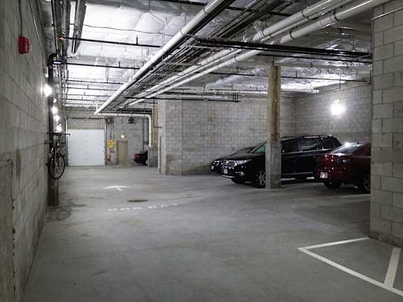 A parking garage with a bicycle and two cars.
